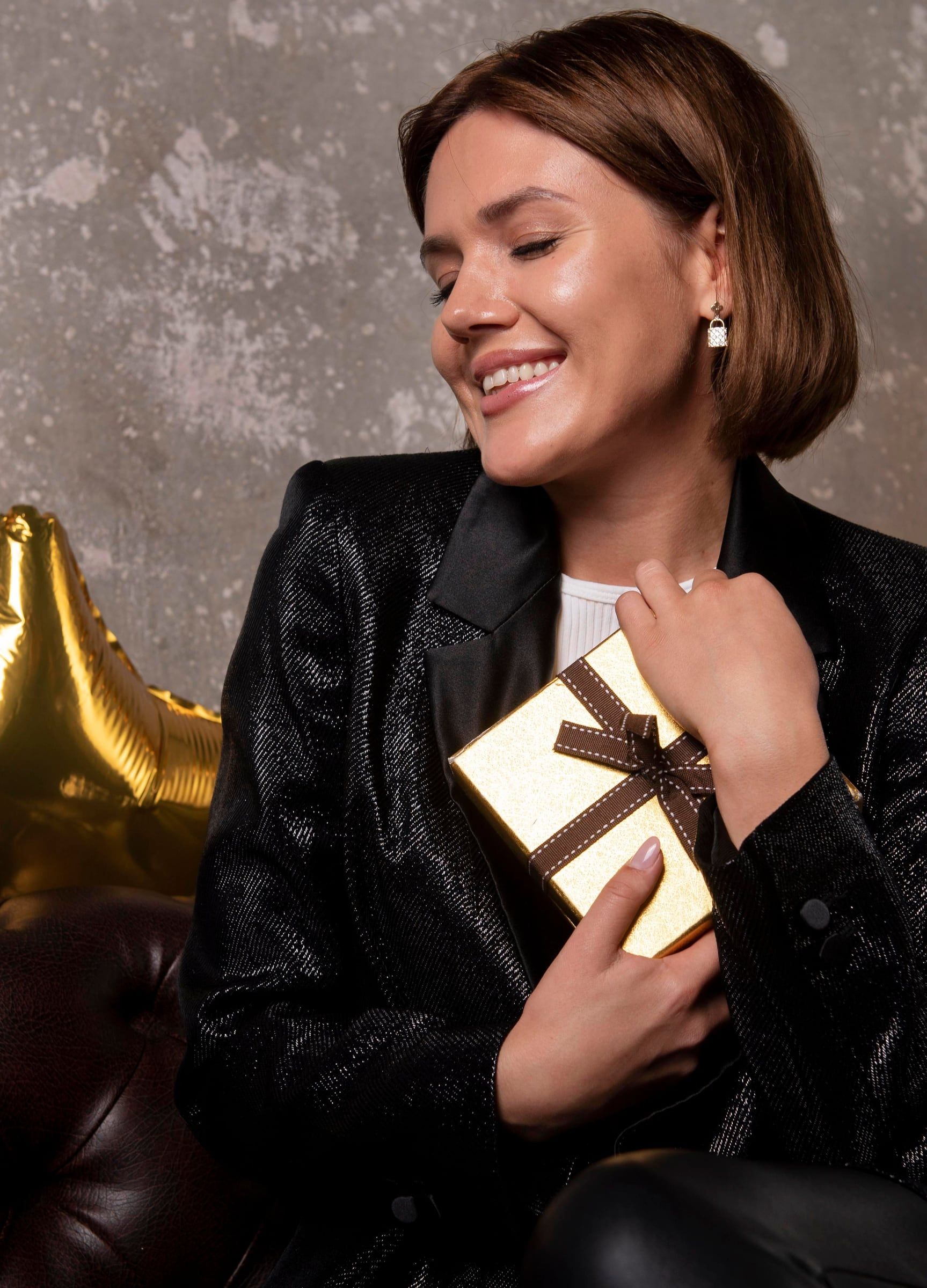 Mujer sonriendo con un regalo de fin de año en caja dorada con lazo
